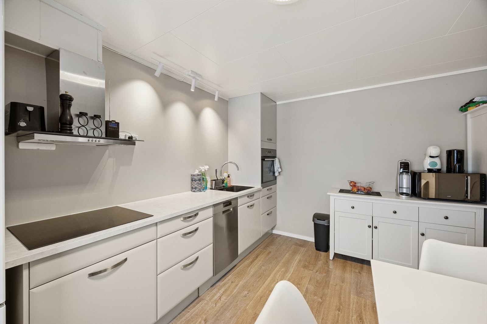 Kjøkkenet har en innredning med hvite glatte fronter og laminat benkeplate. Galleribilde