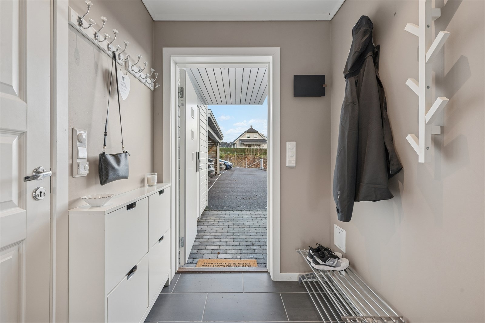 Vel innenfor inngangsdøren møtes man av en lys og moderne entré med flislagt gulv og en moderne fargepalett. Galleribilde