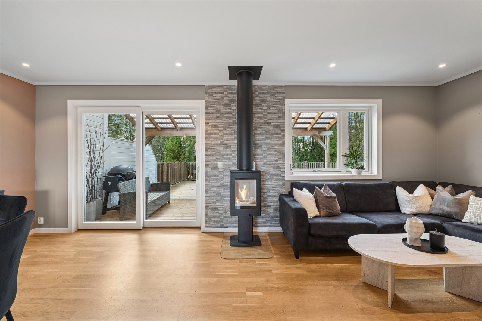 Stuen har store vinduer og skyvedør med utgang til terrasseområdet, som slipper inn mye lys og åpner rommet. Galleribilde