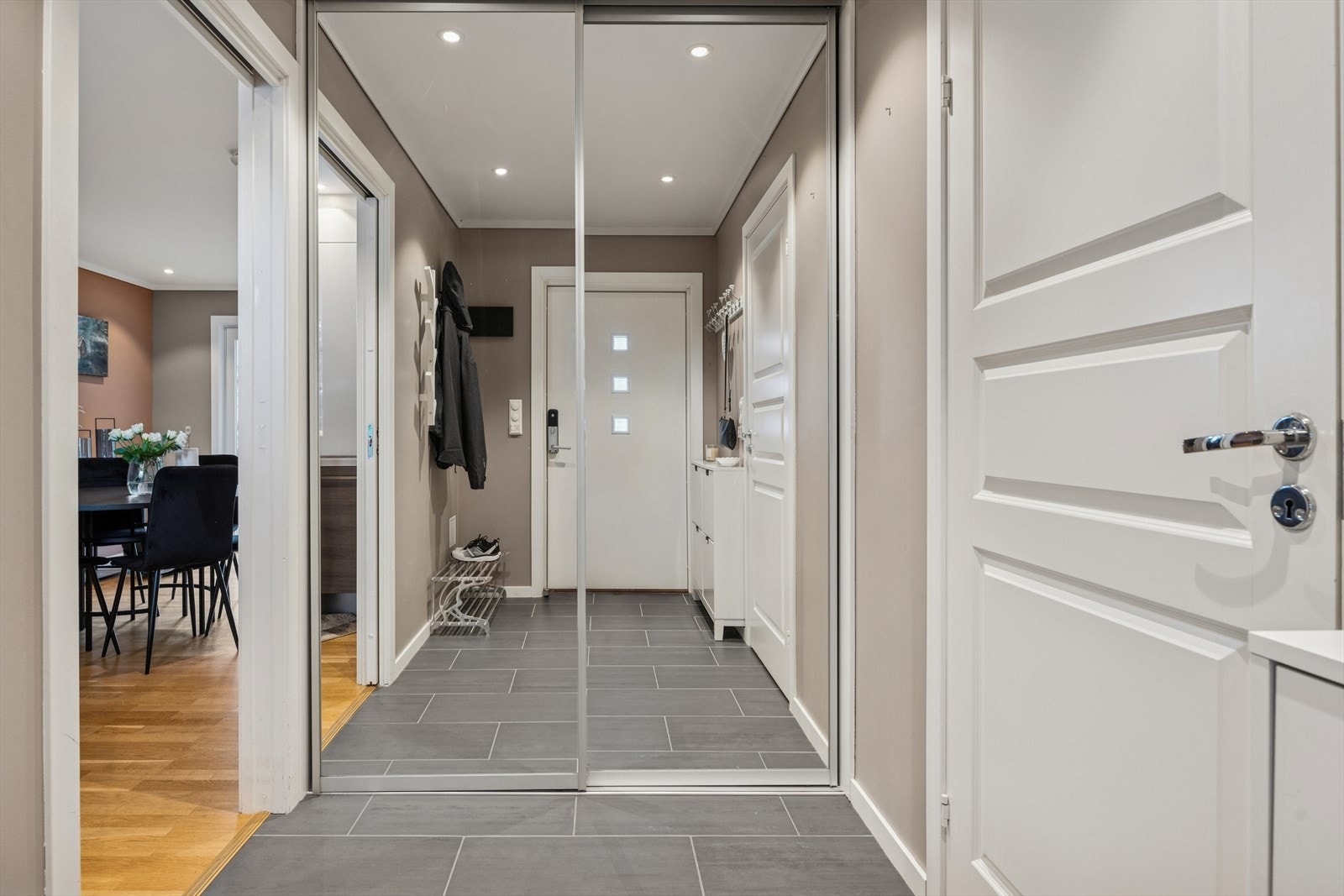 Det er spotbelysning i taket som gir rikelig lys og det er montert en stor skyvedørsgarderobe med speilfront og god plass til oppbevaring av sko og yttertøy. Galleribilde