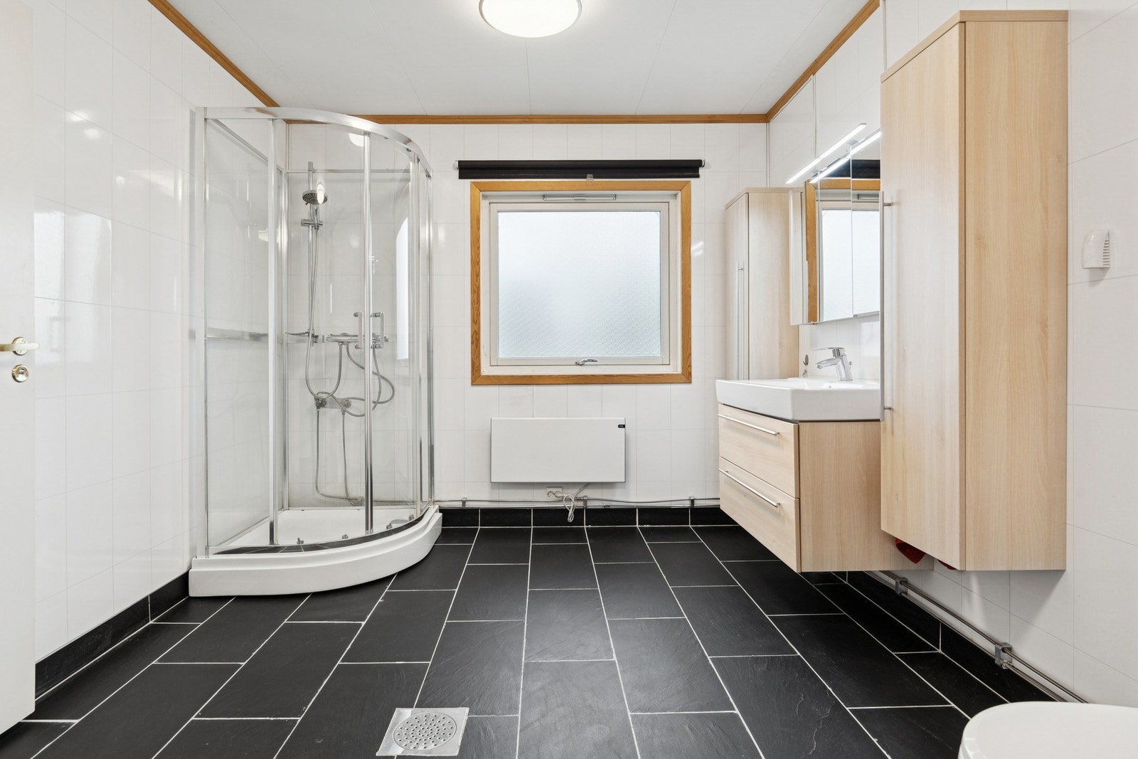 I første etasje finner du et pent bad med flislagt gulv, dusjhjørne, servant med innredning og toalett. Galleribilde