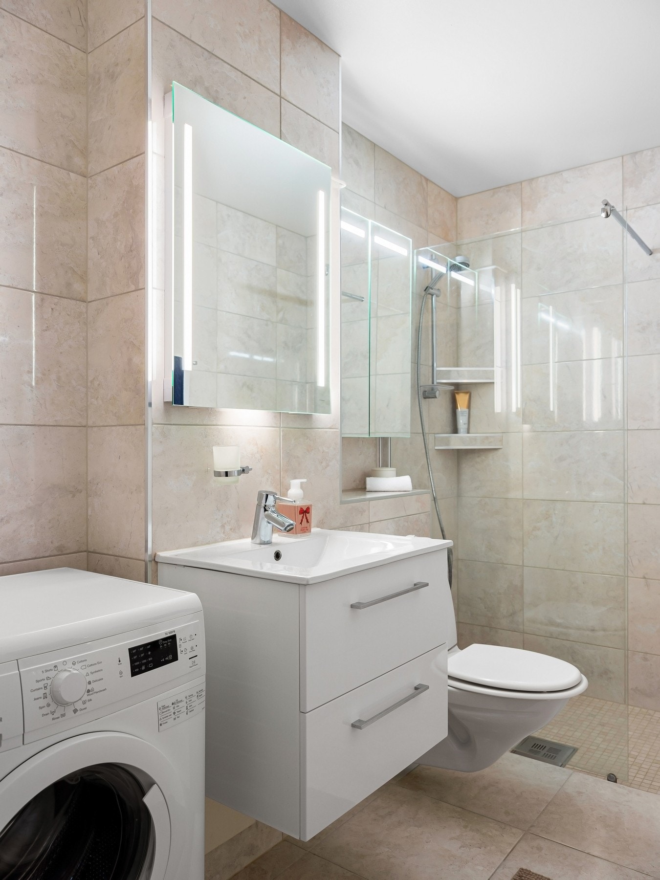 Badet er innredet med servantskap med nedfelt servant, speil med innebygd lys, vegghengt toalett og dusjsone. Galleribilde