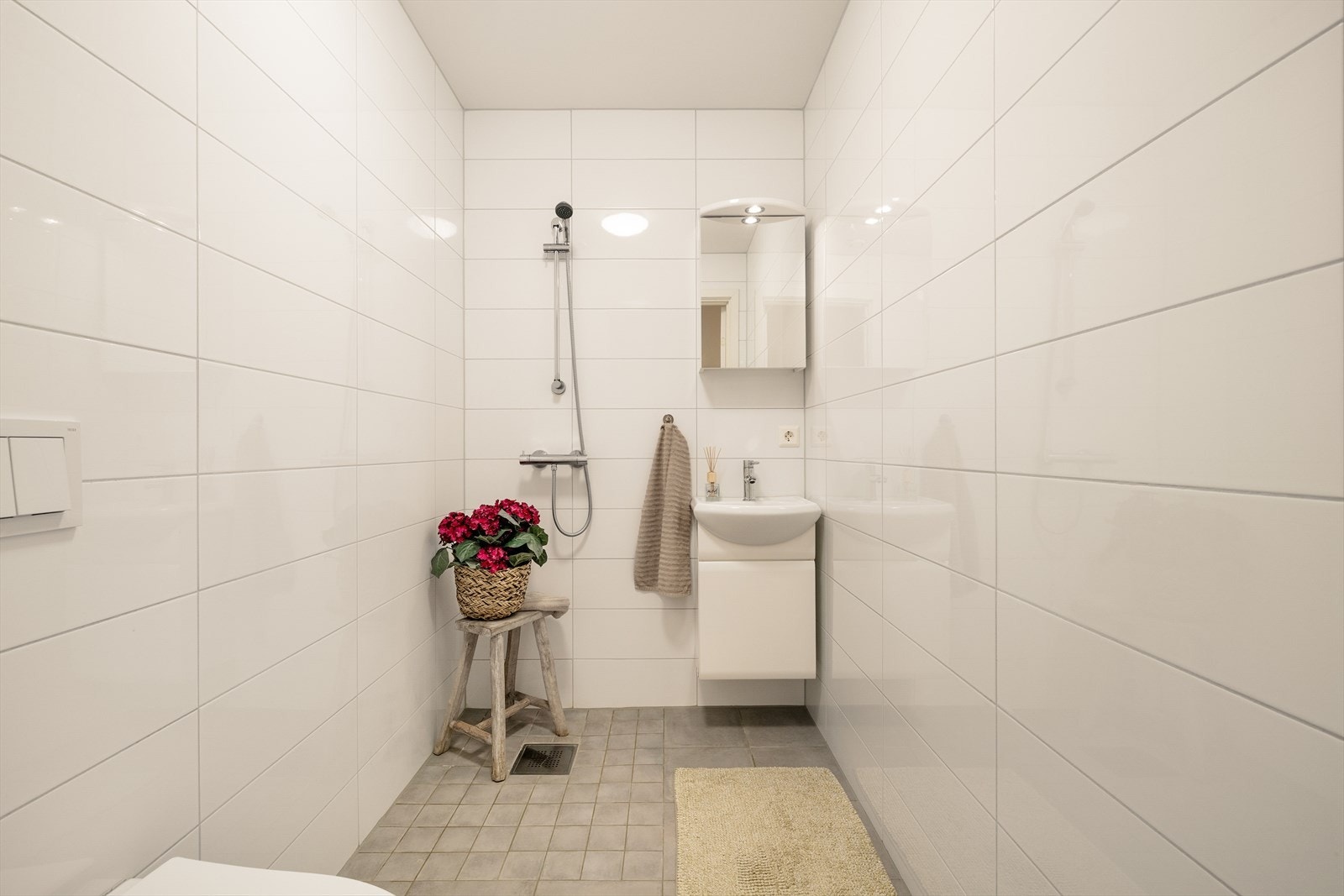 Det andre baderommet har også keramiske fliser på både gulv og vegger, og er innredet med vegghengt toalett, dusjsone med dusjgarnityr, servant med møblement, speil og belysning. Galleribilde