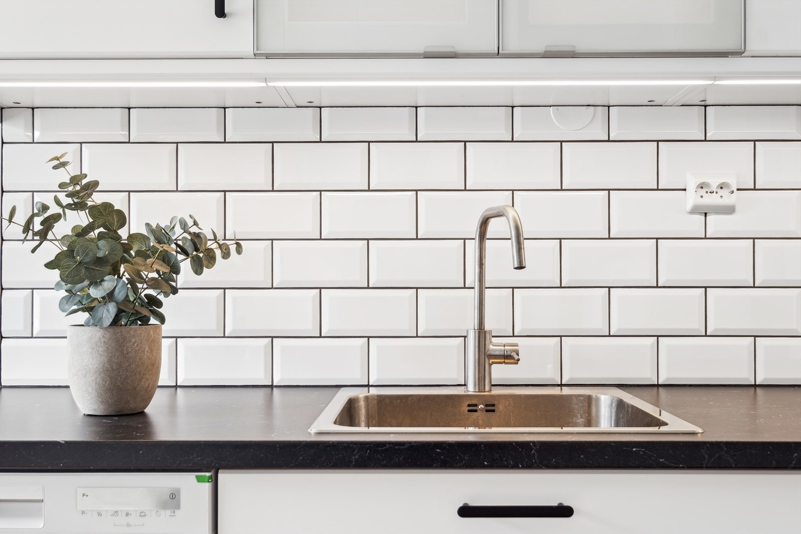 Kjøkkenet er stilrent og funksjonelt, med god skap- og benkeplass Galleribilde