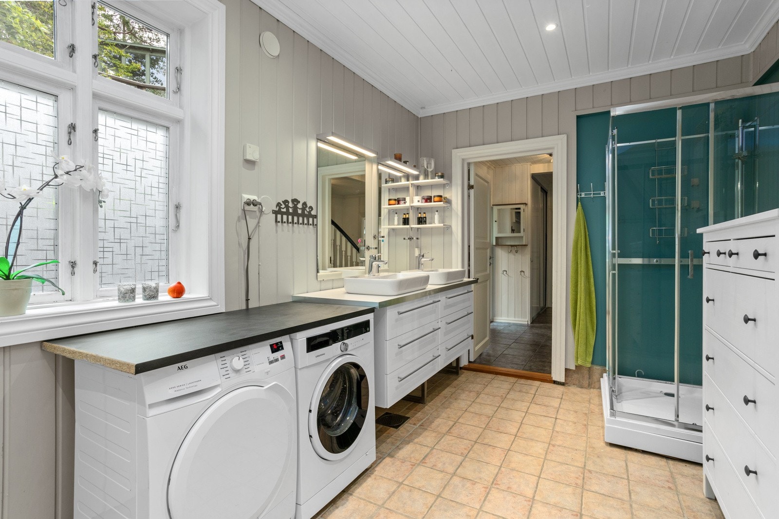 Funksjonelt og praktisk rom for familier med doble servanter, dusj, toalett og opplegg for både vaskemaskin og tørketrommel. Galleribilde