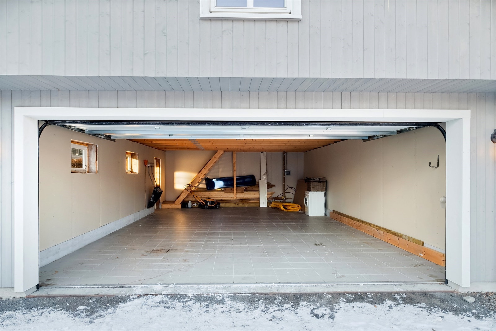Den doble garasjen har flislagt gulv, innlagt strøm og elektrisk portåpner. Galleribilde