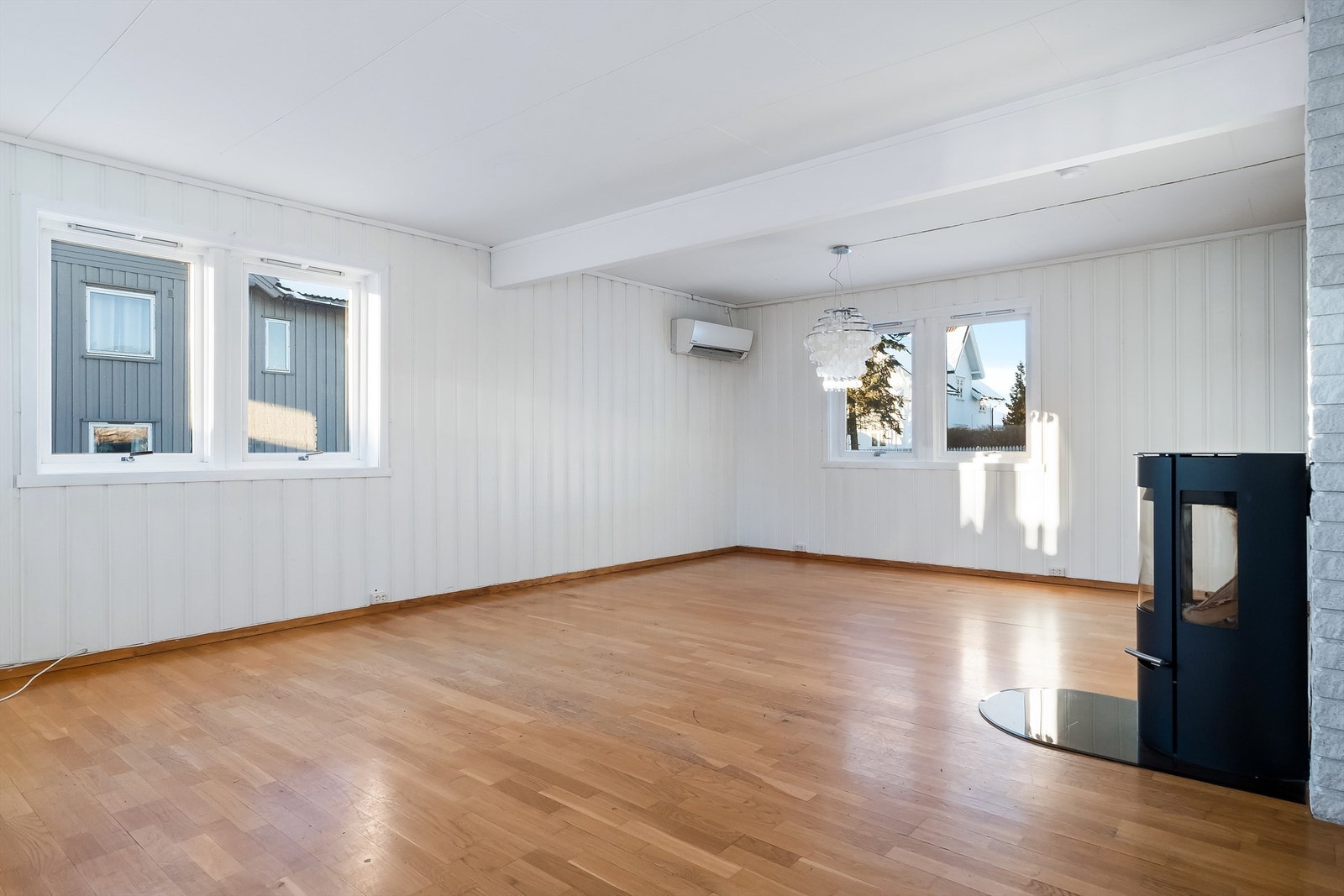 Stuen er et romslig oppholdsrom med parkett på gulvet og flere vinduer. Galleribilde