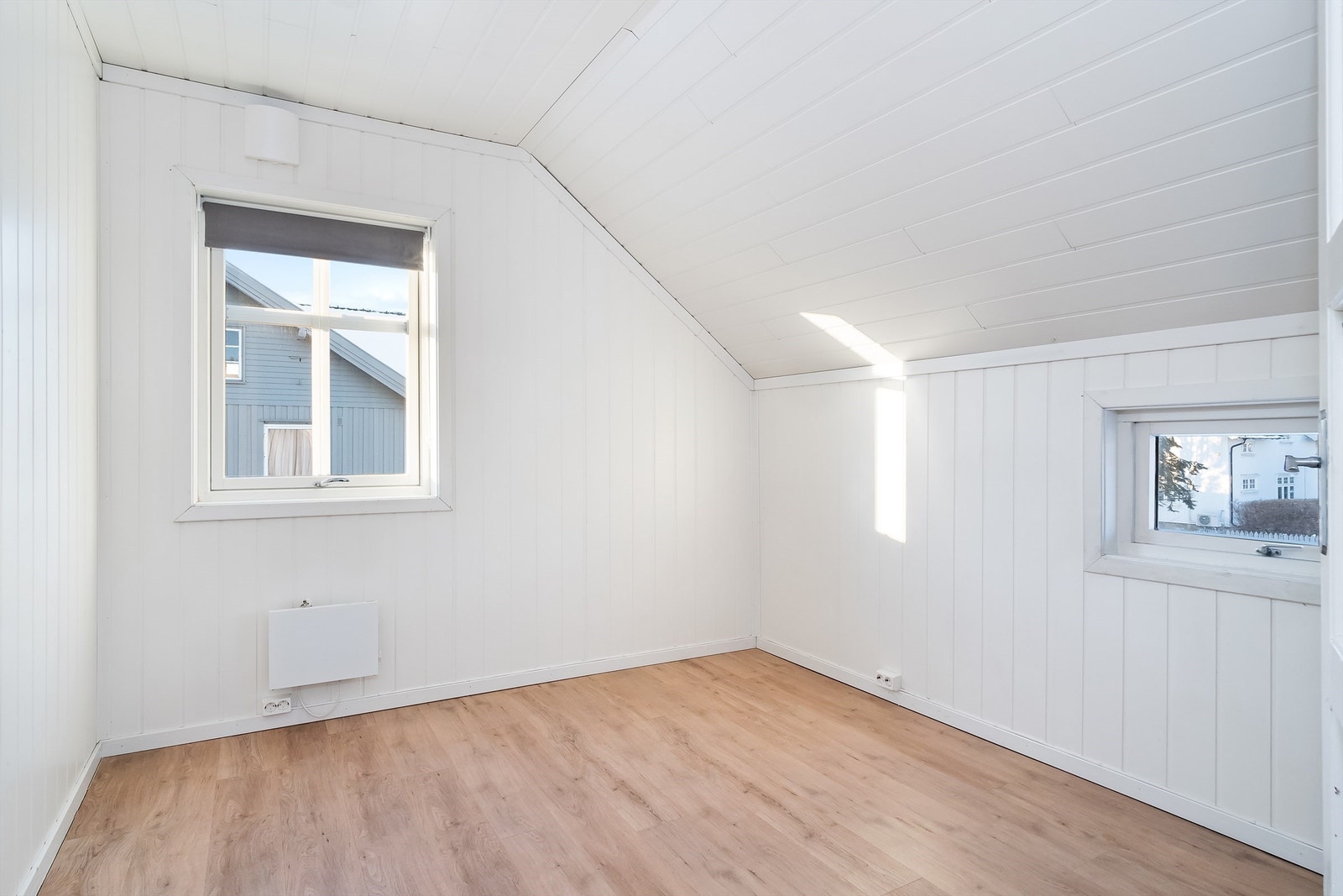 Et lyst soverom med malte panelvegger og laminat på gulvet. Galleribilde