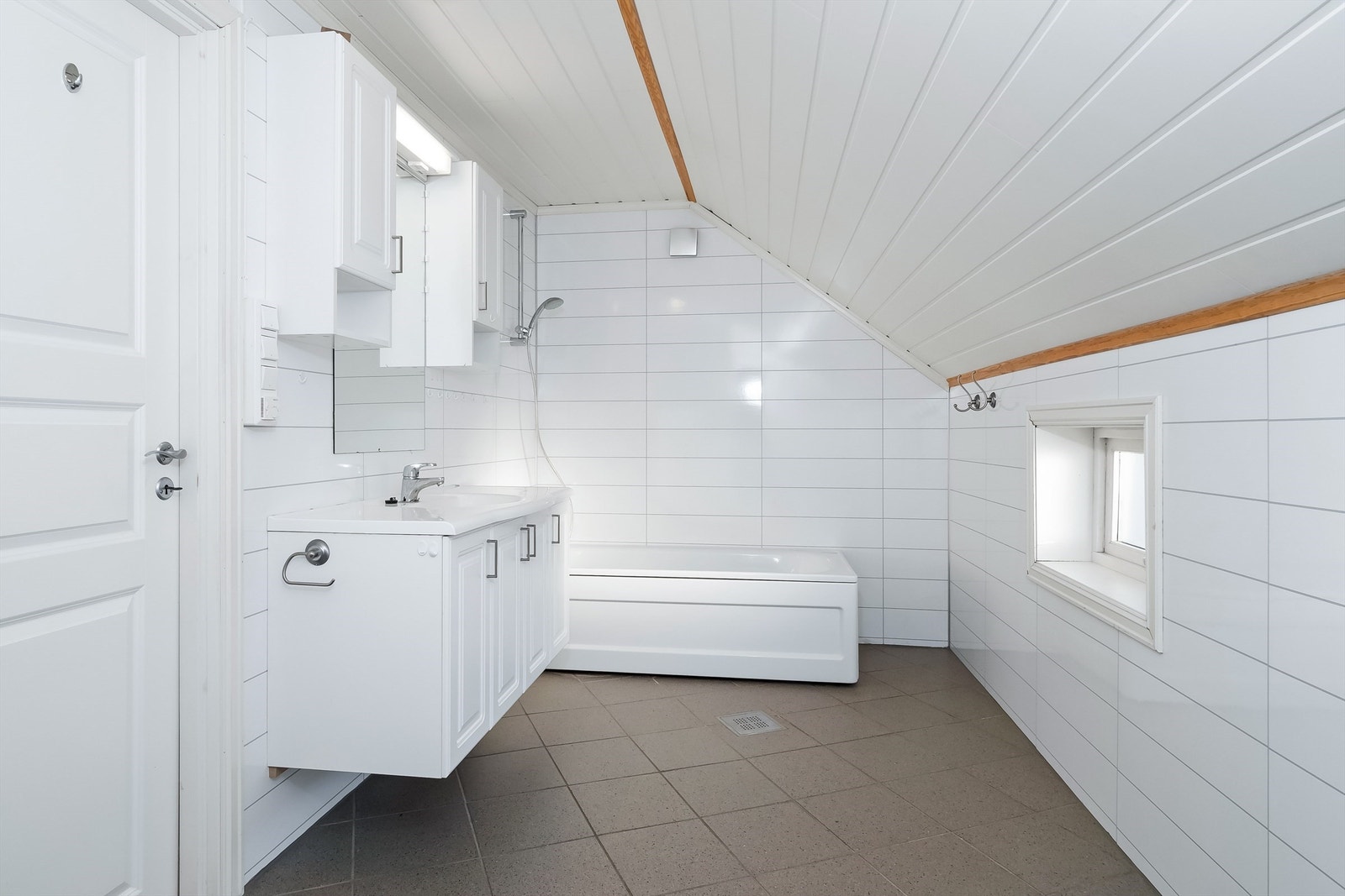 Rommet har baderomsplater på veggene og flislagt gulv med varmekabler. Galleribilde