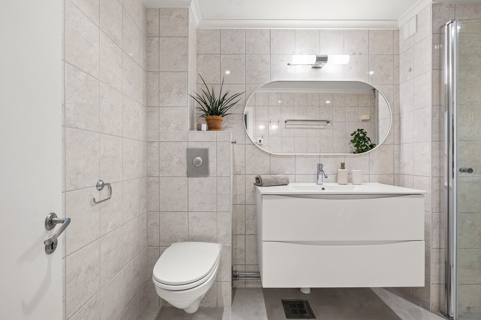 Badet er innredet med servant med innredning, toalett, praktisk dusjhjørne med innfellbare dusjdører og opplegg for vaskemaskin. Galleribilde