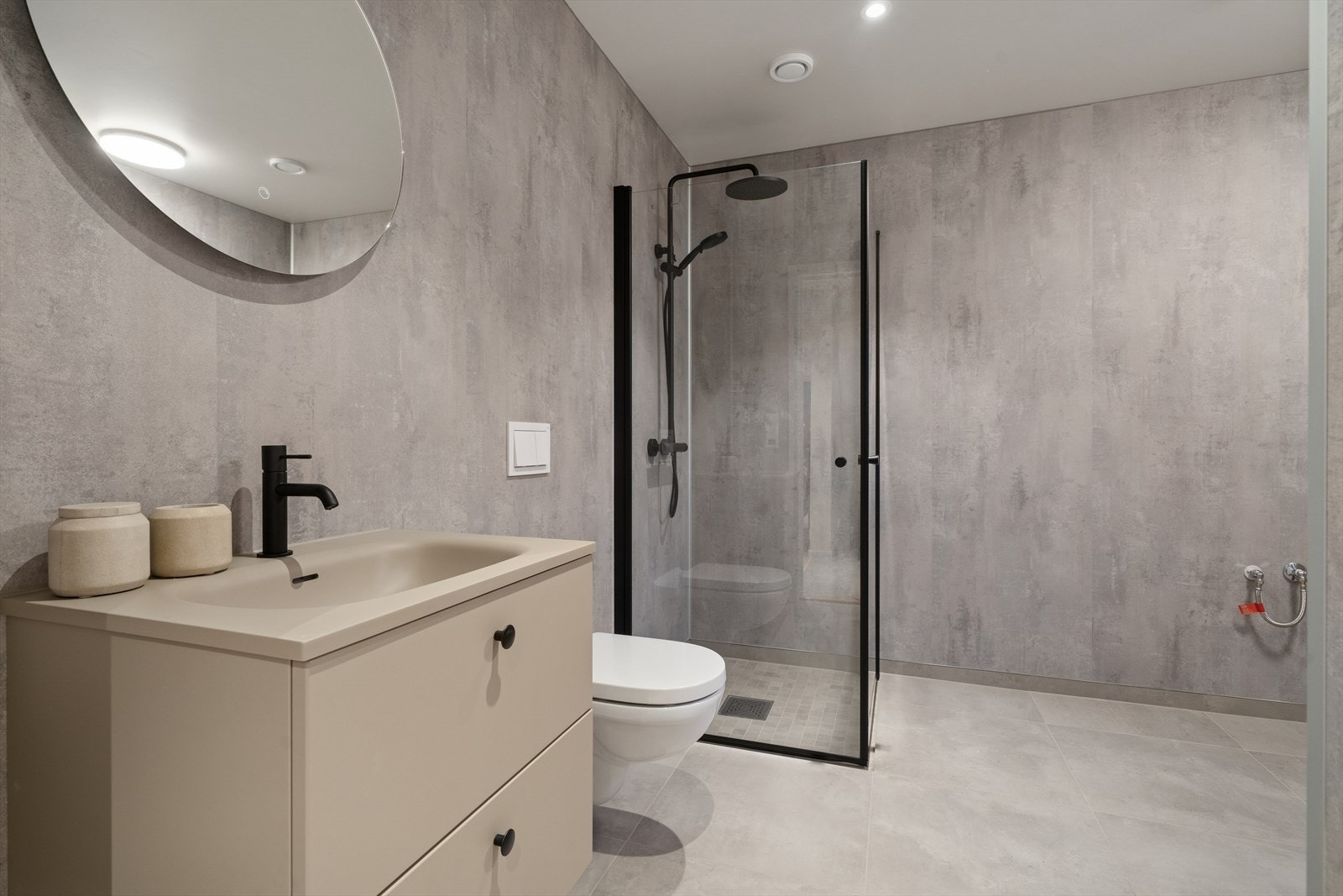 Kombinert bad/vaskerom i 1. etasje. Flislagt gulv og veggplater med betonglook, gir en robust og lettstelt løsning på badet. Galleribilde