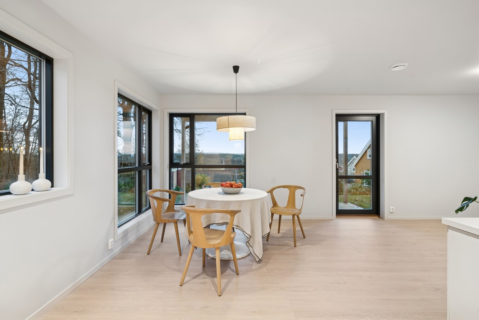 Spiseplassen er omkranset av store vinduer med utsikt mot grøntområde. Galleribilde