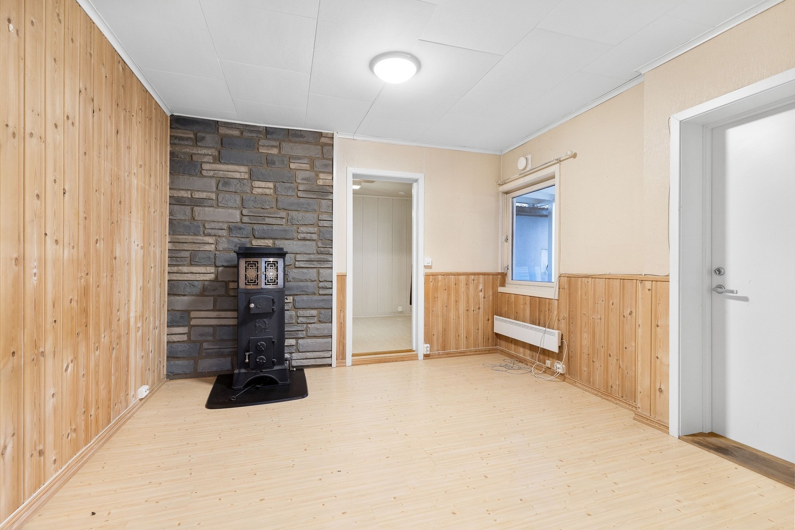 Gang med laminatgulv, og en vedovn foran en steinvegg. Galleribilde