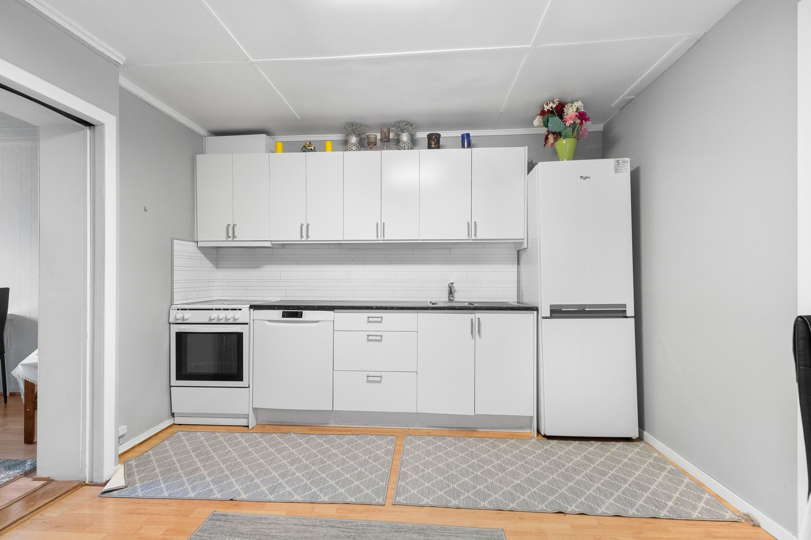 Kjøkken med hvite skap, og plass til kjøleskap, komfyr og oppvaskmaskin. Galleribilde