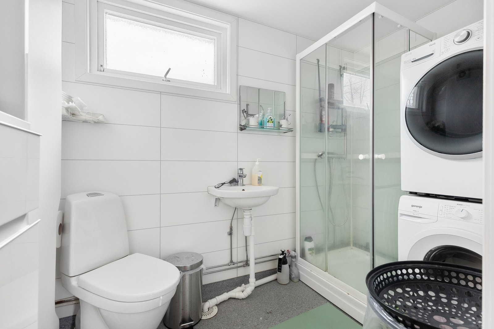 Bad med dusjkabinett, toalett, opplegg for vaskemaskin og tørketrommel samt servant. Galleribilde
