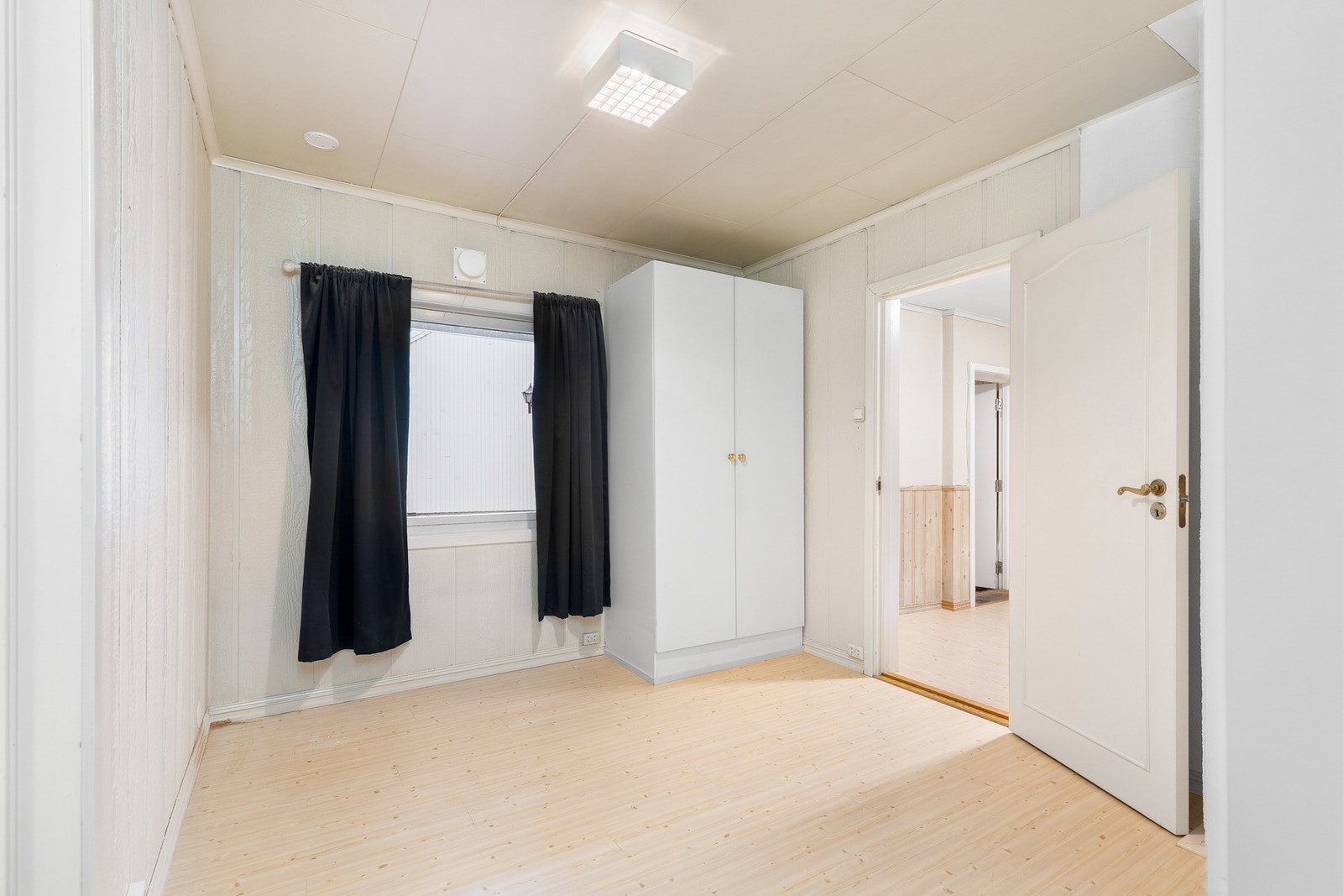 Lyst soverom med laminatgulv og garderobeskap. Galleribilde