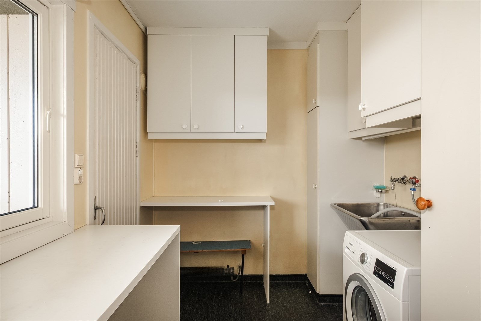 Vaskerommet er praktisk anlagt med benkeplate, skyllekar i stål, opplegg for vaskemaskin, samt også dør ut til bod på altan. Galleribilde