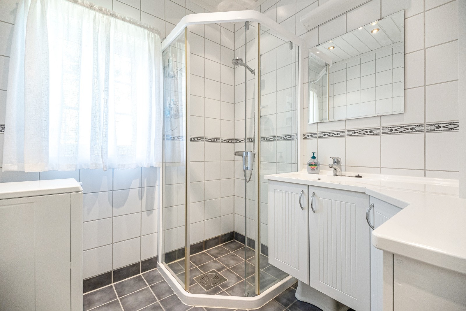 Hjørneservantskap som gir praktisk oppbevaringsplass samtidig som det utnytter rommets form på en effektiv måte. Dusjnisjen har skyvedører Galleribilde