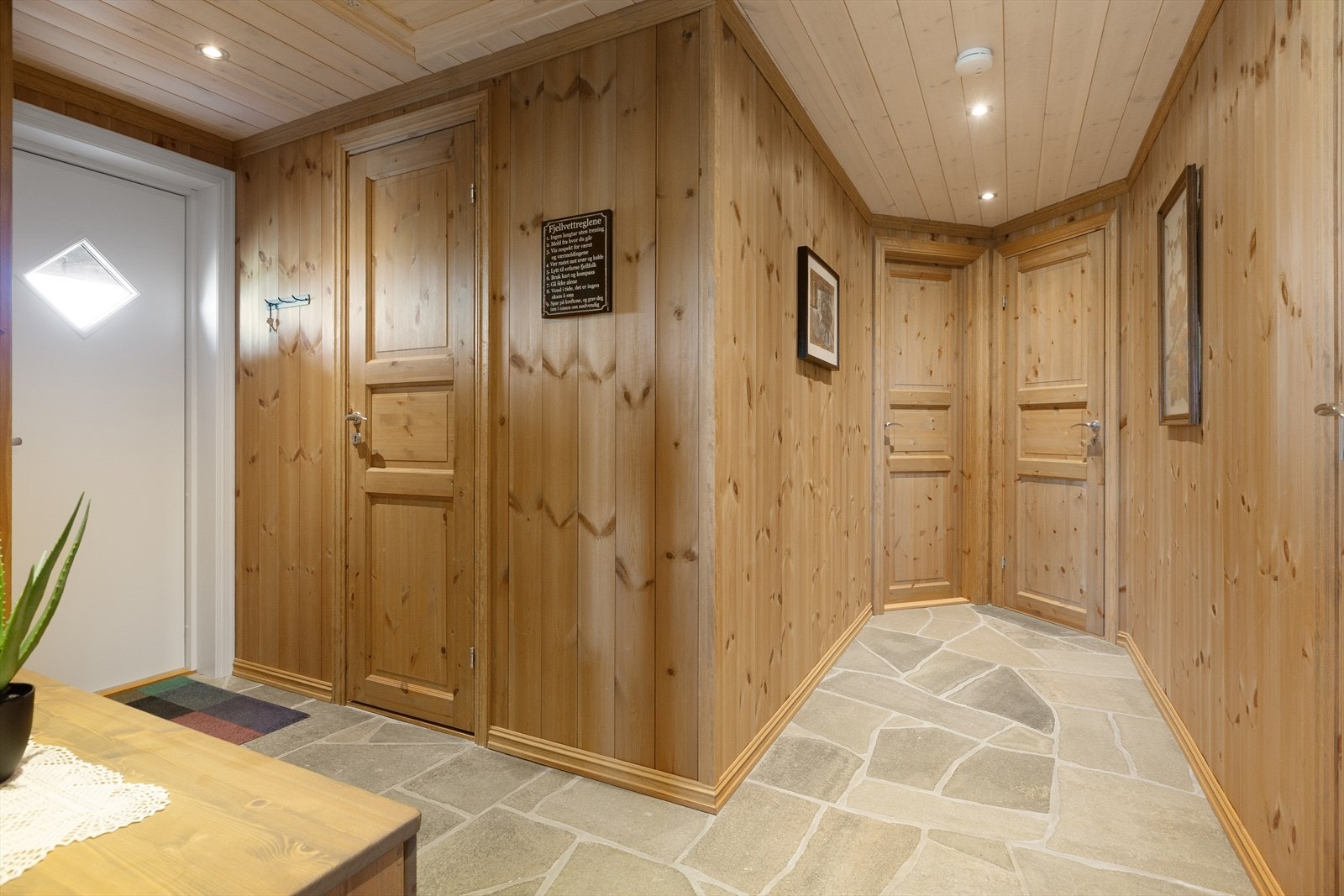 Fra hyttas overbygde inngangsparti kommer en inn i entré med plassbygd garderobeskap med sittebenk og skuffer i heltre. Galleribilde