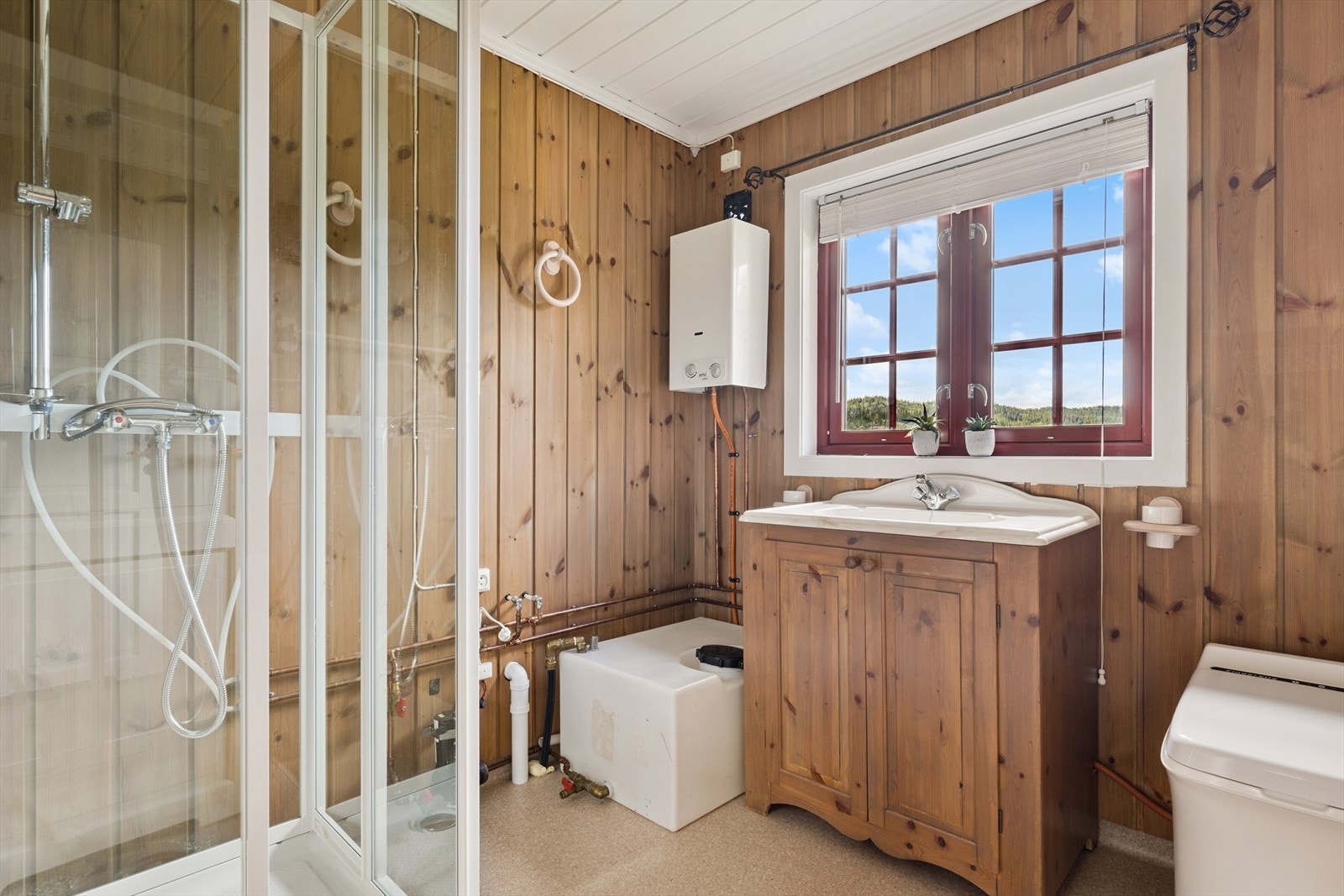 Badet er enkelt, men funksjonelt, med servantskap, dusjkabinett og Cinderella forbrenningstoalett. Galleribilde