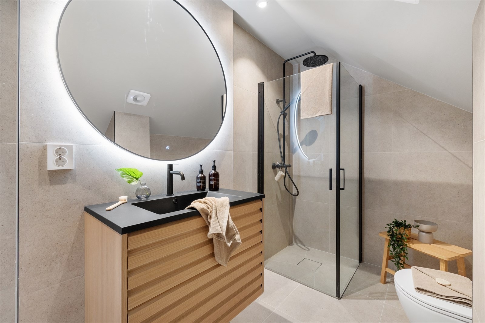 Badet har et delikat og tidløst uttrykk, og er utstyrt med vegghengt toalett, dusj med glassdører og servant med moderne innredning. Galleribilde