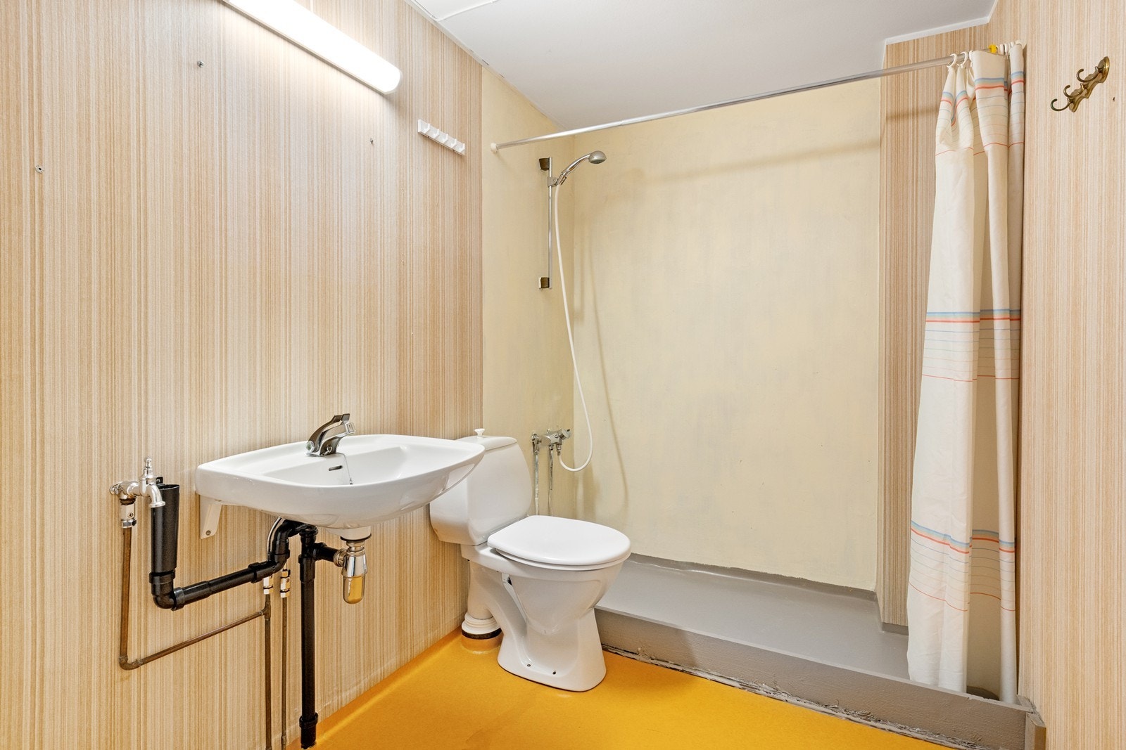 Badet har servant, toalett og dusjnisje med forheng og opplegg for vaskemaskin. Galleribilde