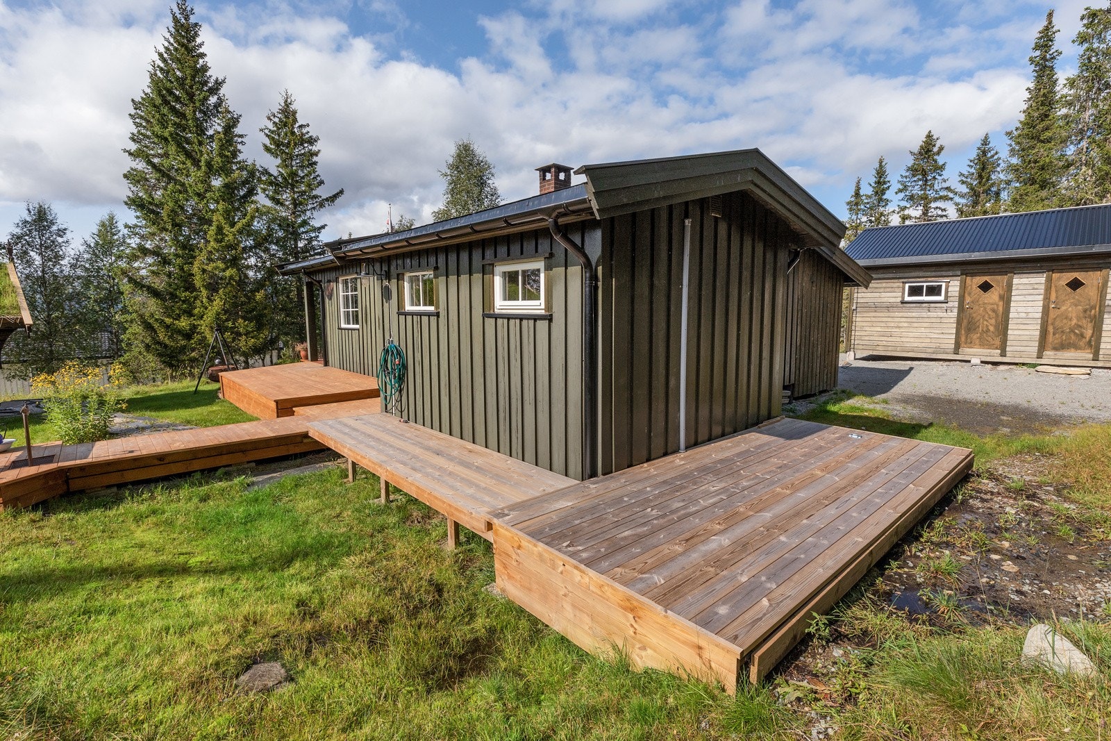 Utenfor hytta er det fra terrasse laget platting på to sider til av hytta Galleribilde