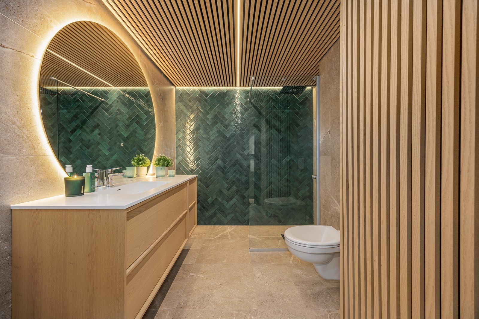 Eksklusivt baderom med spilehimling, fliser i varme naturtoner og moderne innredning med store speilflater og god belysning. Galleribilde