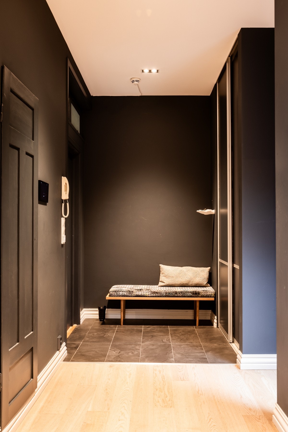 Praktisk entré med sittebenk, skyvedørsgarderobe og flislagt gulv. Galleribilde