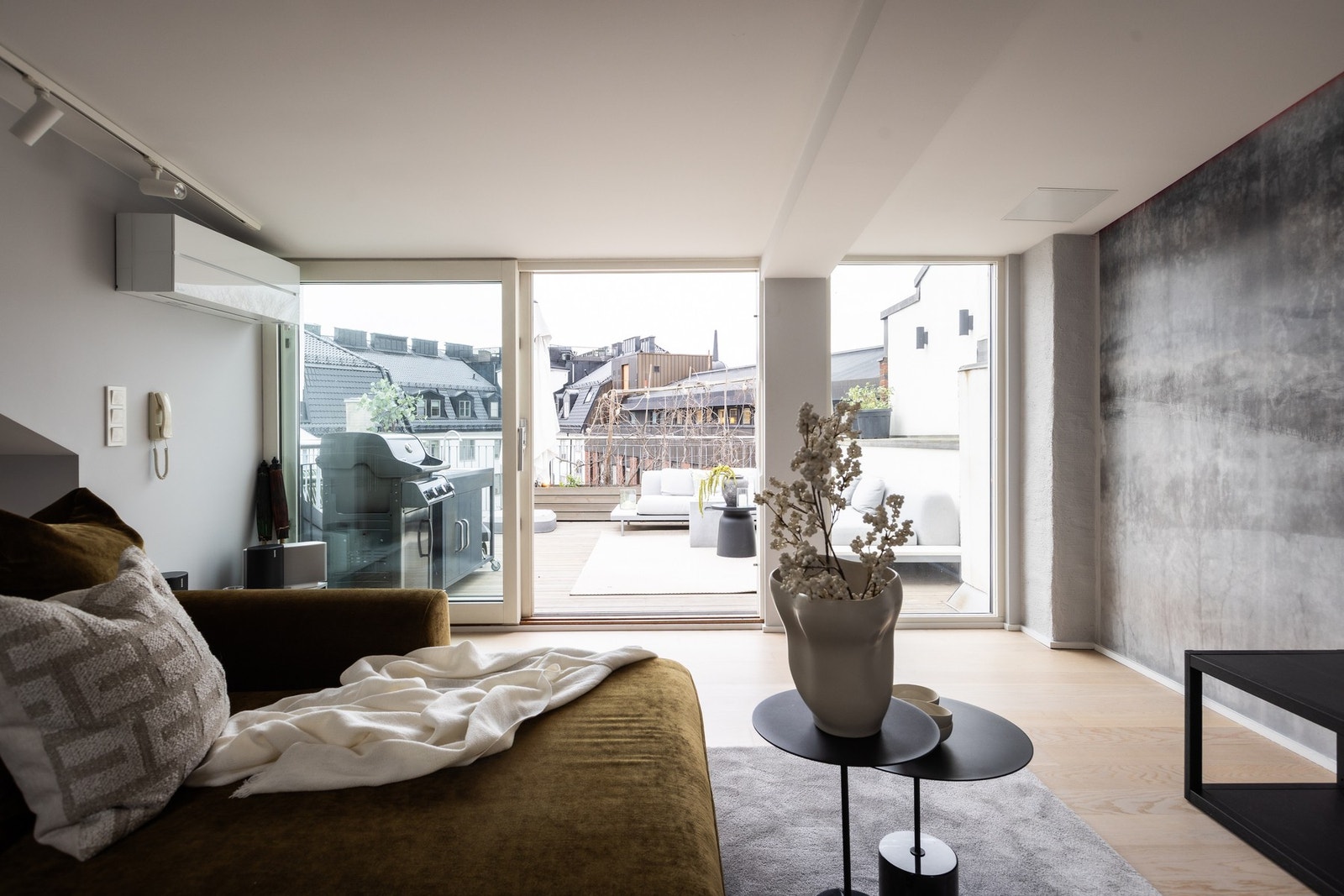 Behagelig sitteområde med store glassflater som åpner rommet mot terrassen og utsikt over byens tak. Galleribilde