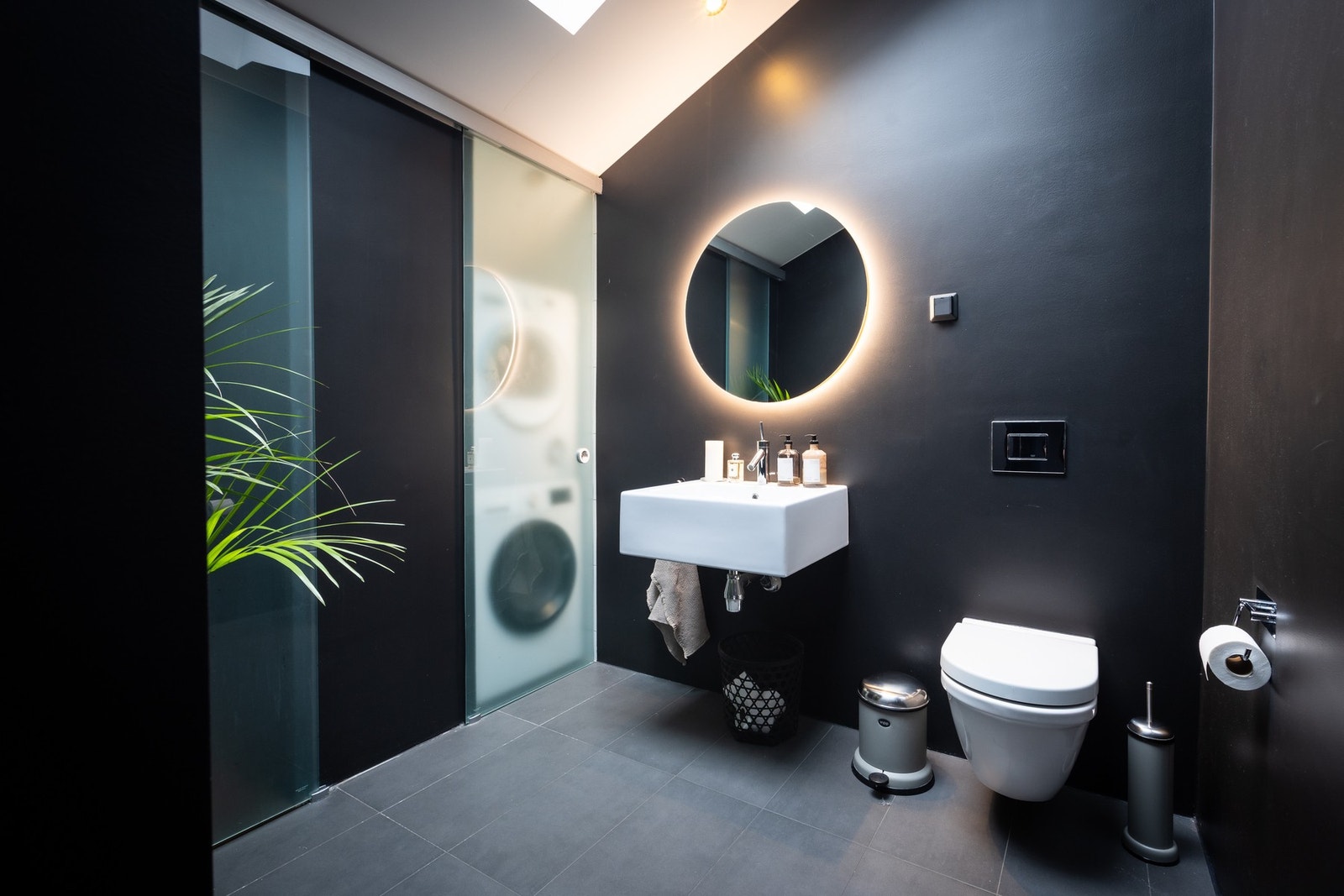 Eksklusivt hovedbad med vegghengt toalett, servant, rundt speil med integrert belysning, dusj og egen nisje med vaskemaskin og tørketrommel bak glassdør (bad nr 2). Galleribilde