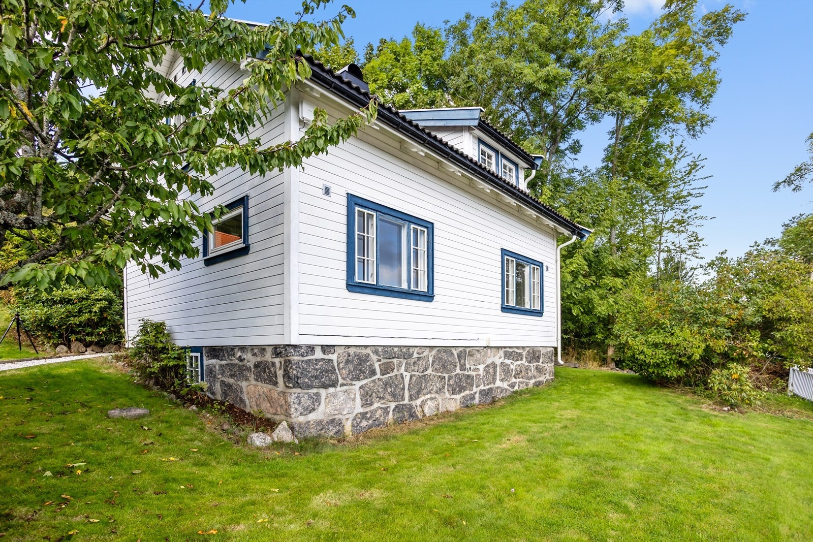 Tomten er noe skrånende, men er i hovedsak opparbeidet med plenarealer rundt huset og i stor utstrekning innrammet av hekk og gjerde. Galleribilde