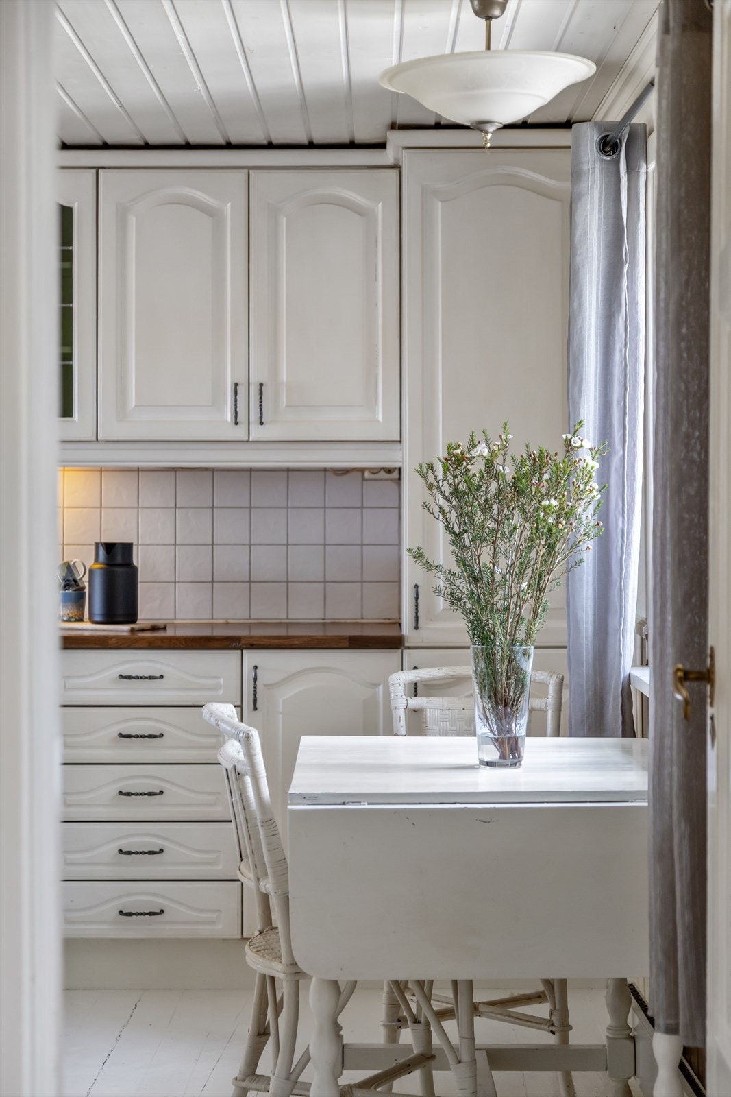 Innredningen har malte, hvit fronter som matcher det øvrige stiluttrykket i hjemmet. De mørke og laminerte benkeplatene skaper kontrastfarge mot de ellers så lyse fargene i rommet. Galleribilde