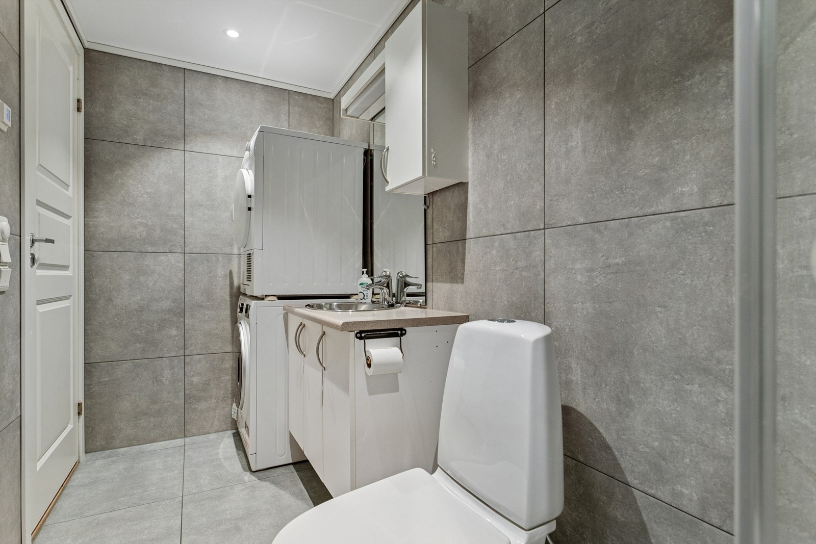 Badet er utstyrt med dusjhjørne, wc, opplegg for vaskemaskin/tørketrommel og lys baderomsinnredning. Galleribilde