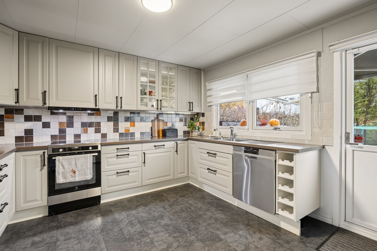 Kjøkkenet er av god størrelse og har en praktisk innredning med profilerte fronter, laminat benkeplate og fliser bak vask og benk Galleribilde