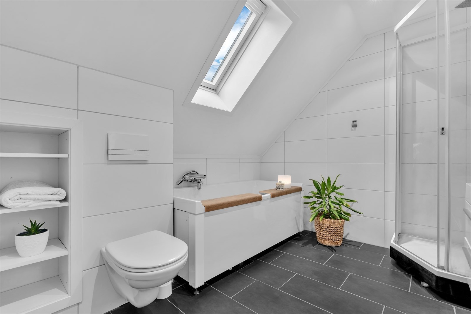 Det inneholder vegghengt toalett, badekar, dusjkabinett og en innredning med dobbel servant, som gir både stil og funksjonalitet. Galleribilde