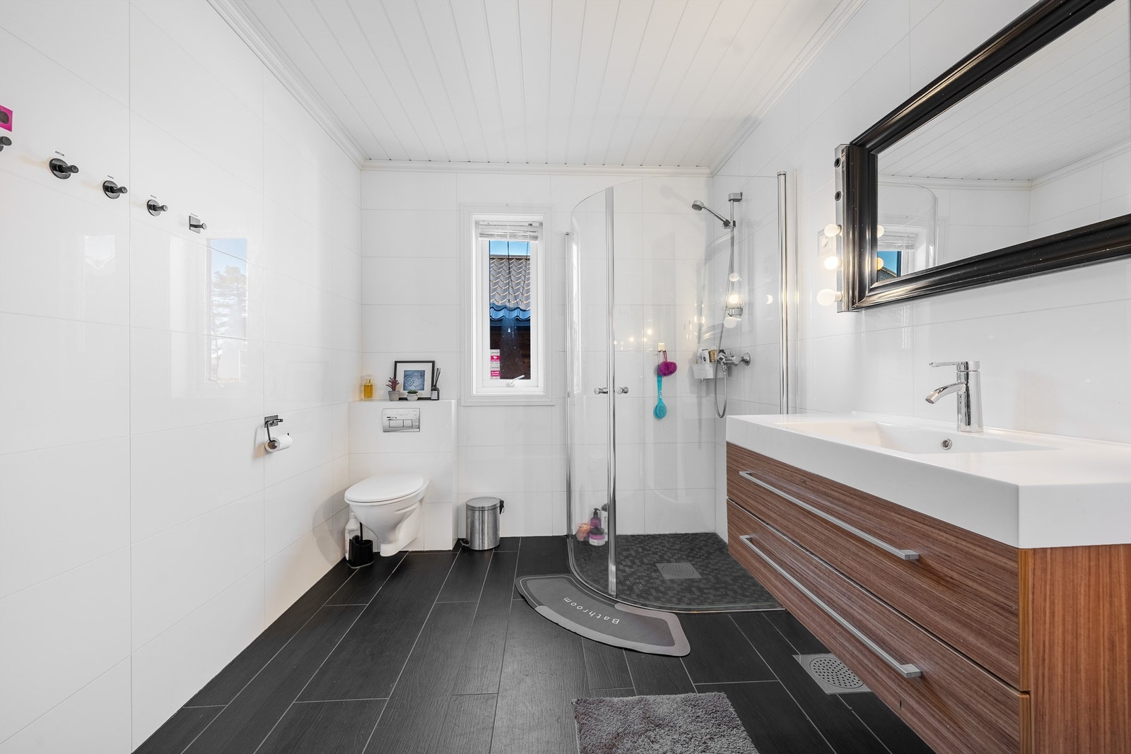 Bad med dusjhjørne, servant med skuffer og vegghengt wc. Galleribilde