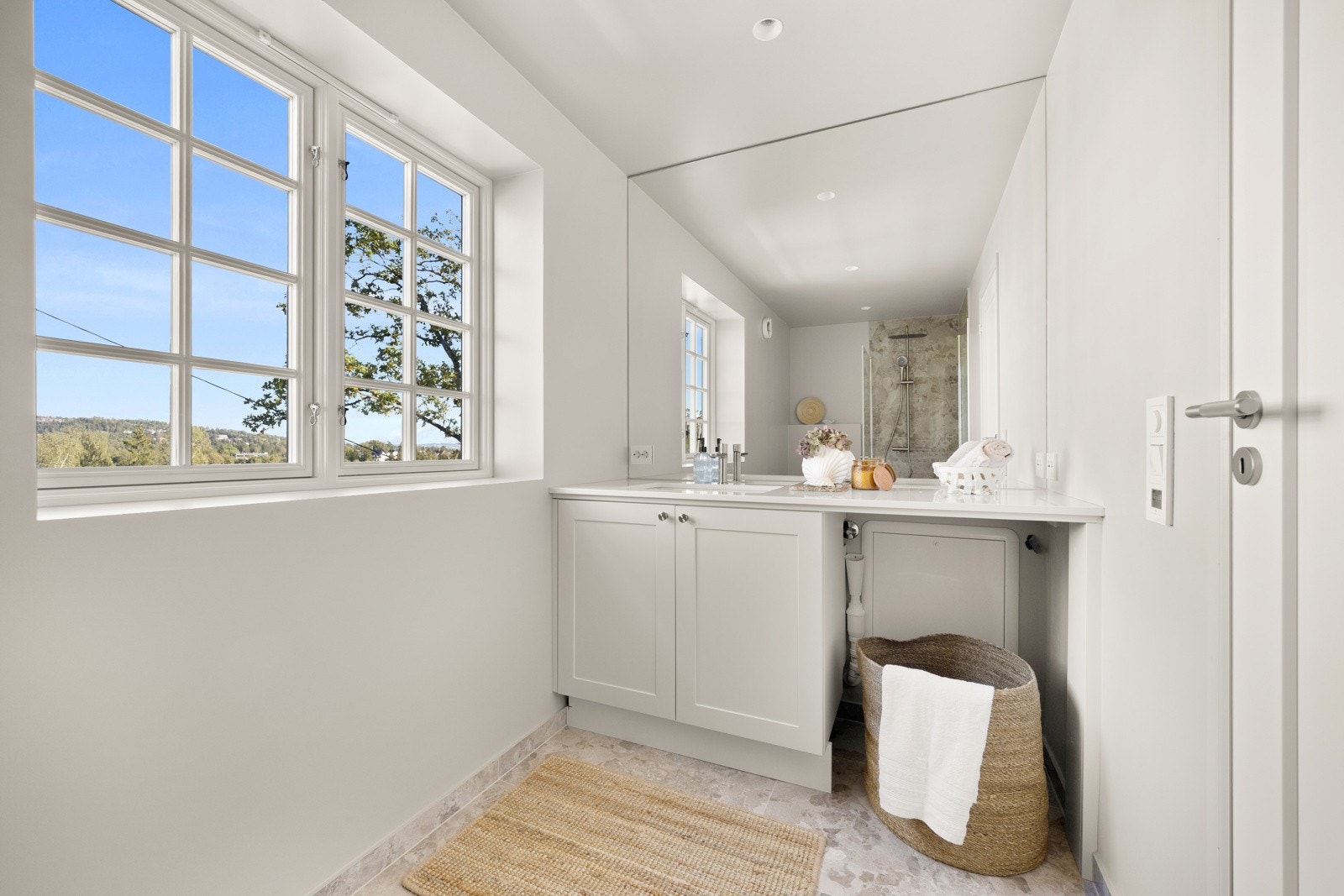 Badet i 2. etasje er lyst og moderne, innredet medet stort speil over servantinnredningen, skapplass under servanten og opplegg for vaskemaskin integrert under benken. Galleribilde