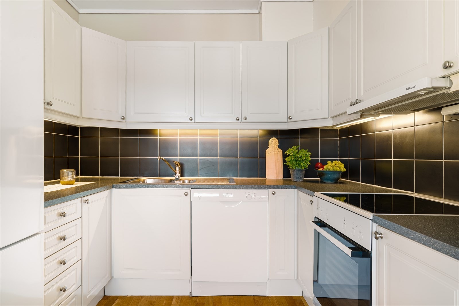 Lys og tidløs kjøkkeninnredning med profilerte fronter og slitesterk laminat benkeplate. Avbildede hvitevarer medfølger i handelen. Galleribilde