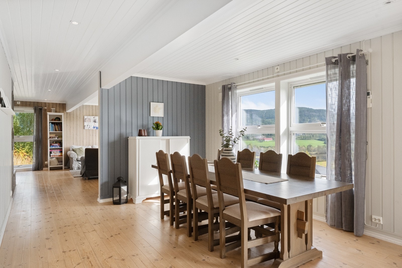 Videre inn i en romslig stue med peis og gode møbleringsmuligheter Galleribilde