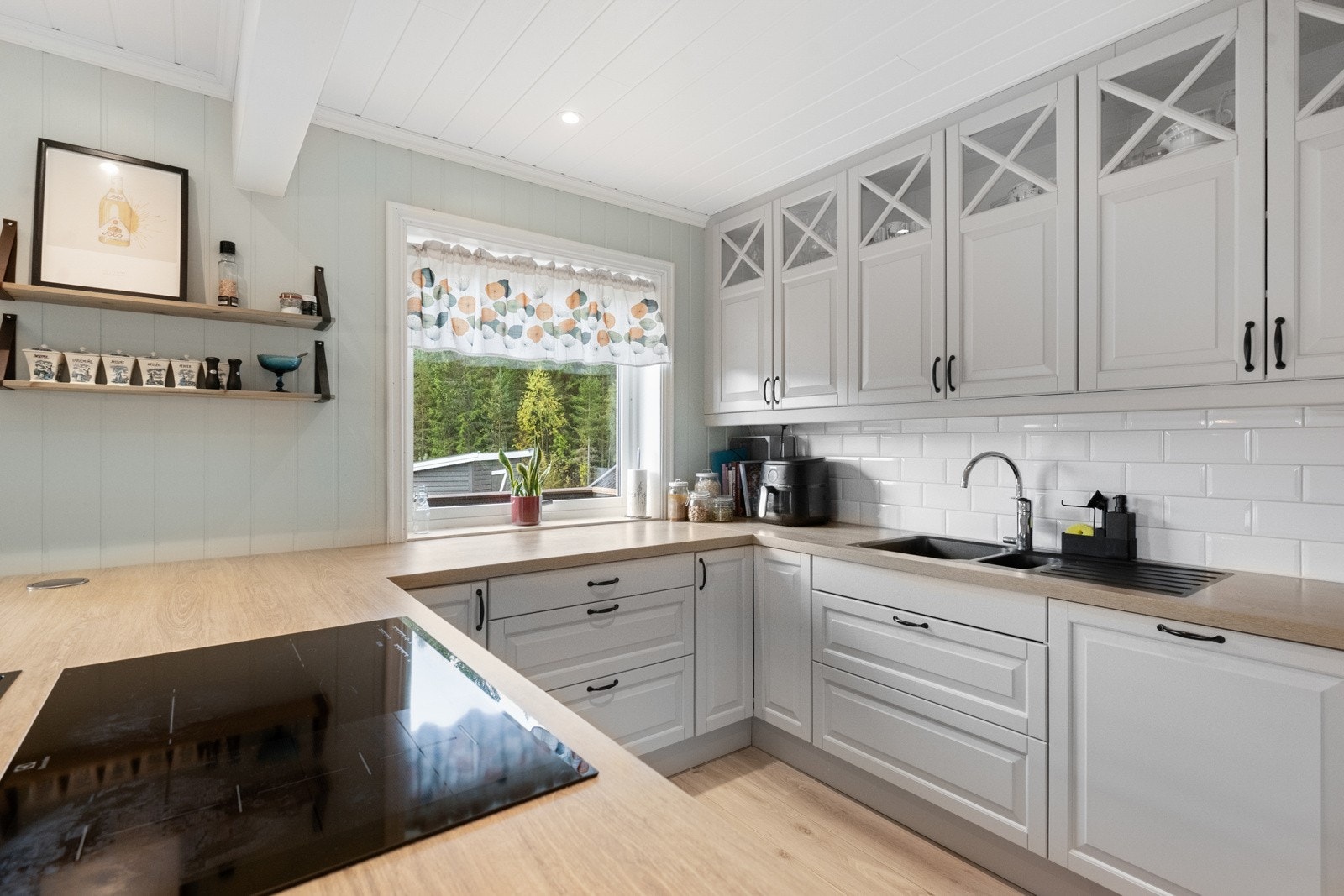 Kjøkkenet ble oppgradert i 2018 og har moderne, profilerte fronter, benkeplate med nedfelt vask og platetopp, samt plass til både oppvaskmaskin, stekeovn og kjøleskap Galleribilde