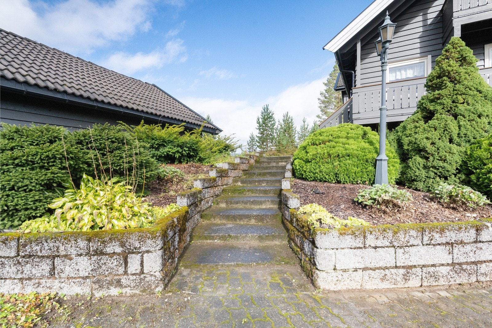 Tomten er tilnærmet flat/slakt skrånet på overflater. Opparbeidelse med plen, grus, belegningsstein og diverse beplantning Galleribilde