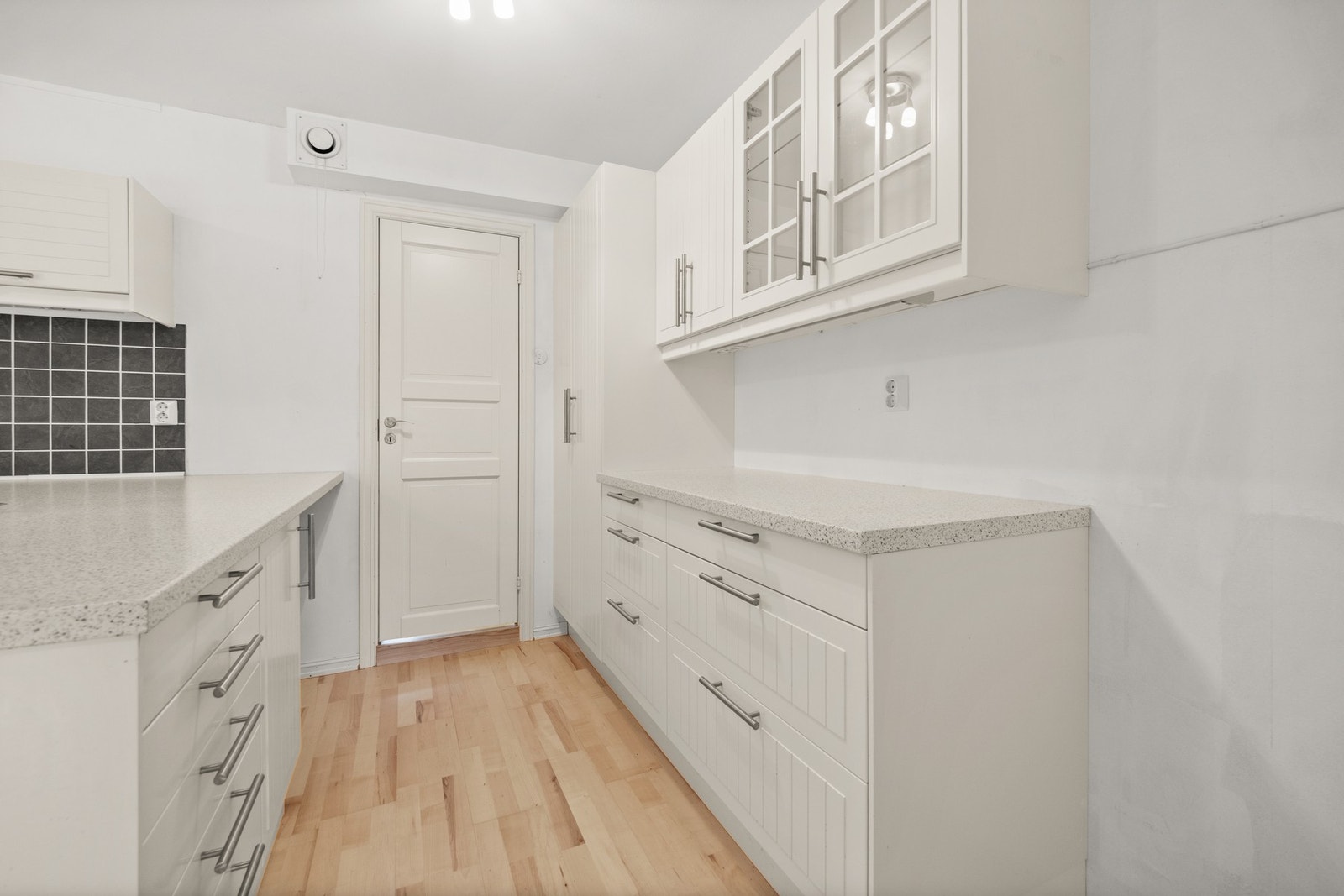 Innredningen har laminerte skrog og profilerte fronter, samt en benkeplate i laminat med nedfelt oppvaskkum og fliser på veggen over. Galleribilde