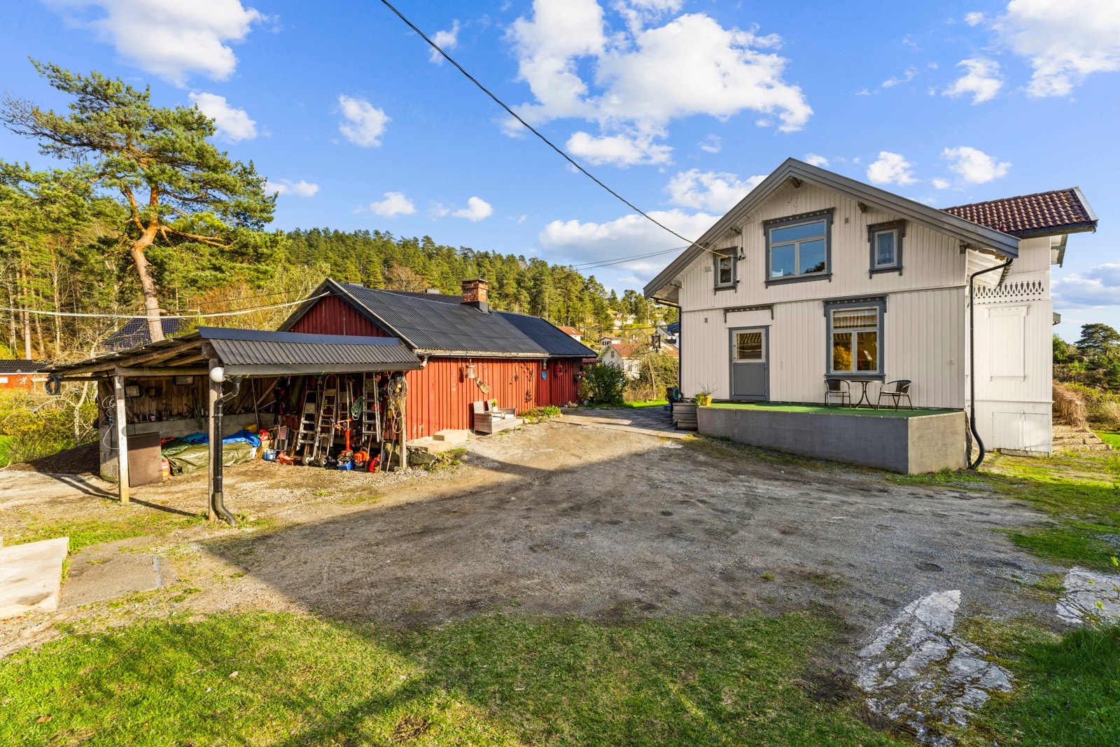 Stor gårdsplass med plass til flere biler. Her er også en carport som forlengelse av bryggerhuset Galleribilde