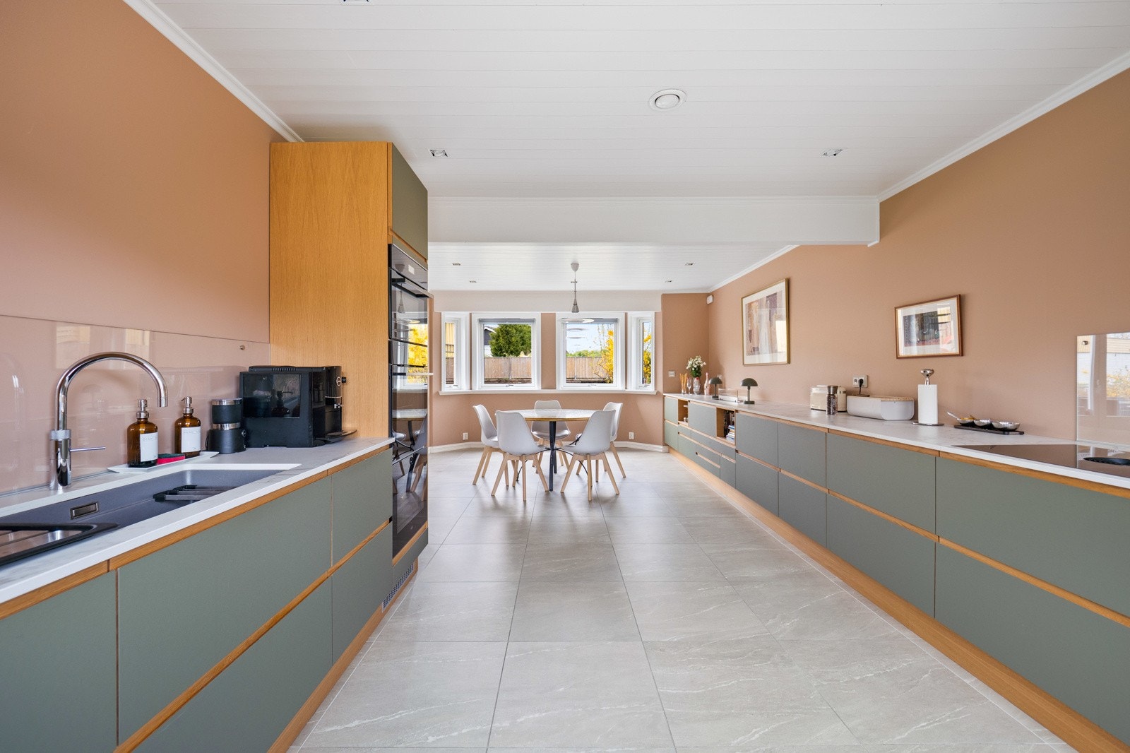 Kjøkkenet har underlimt vaskekum, backsplash i glass, samt trehvite dekksider og innenforliggende lister. Galleribilde