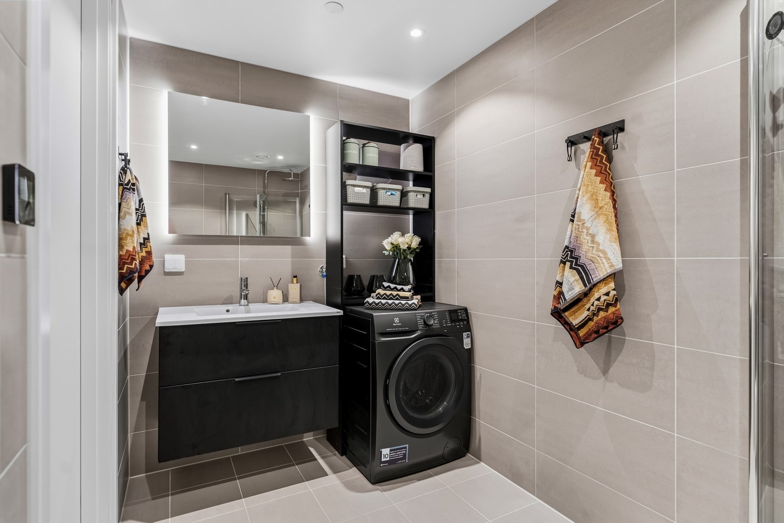 Fra gangen er det inngang til et delikat flislagt baderom. Over servanten er det hengt opp speil med belysning. Galleribilde