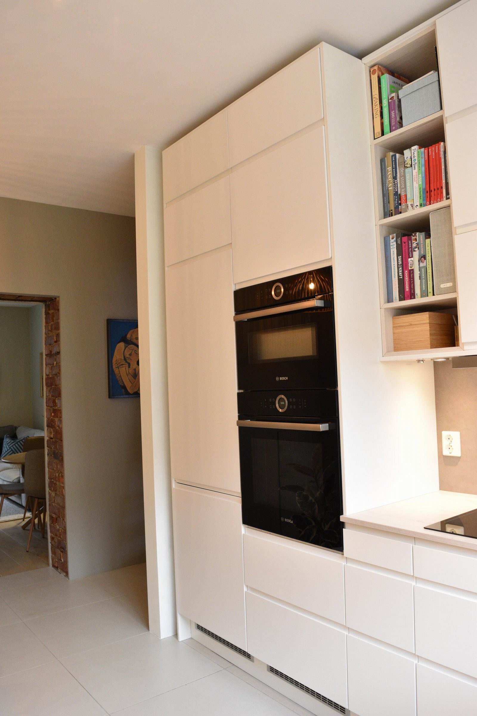 Kjøkkenet er utstyrt med moderne og integrerte hvitevarer, inkludert både fryseskap og kombinert kjøl-/fryseskap, oppvaskmaskin, platetopp og stekeovn Galleribilde