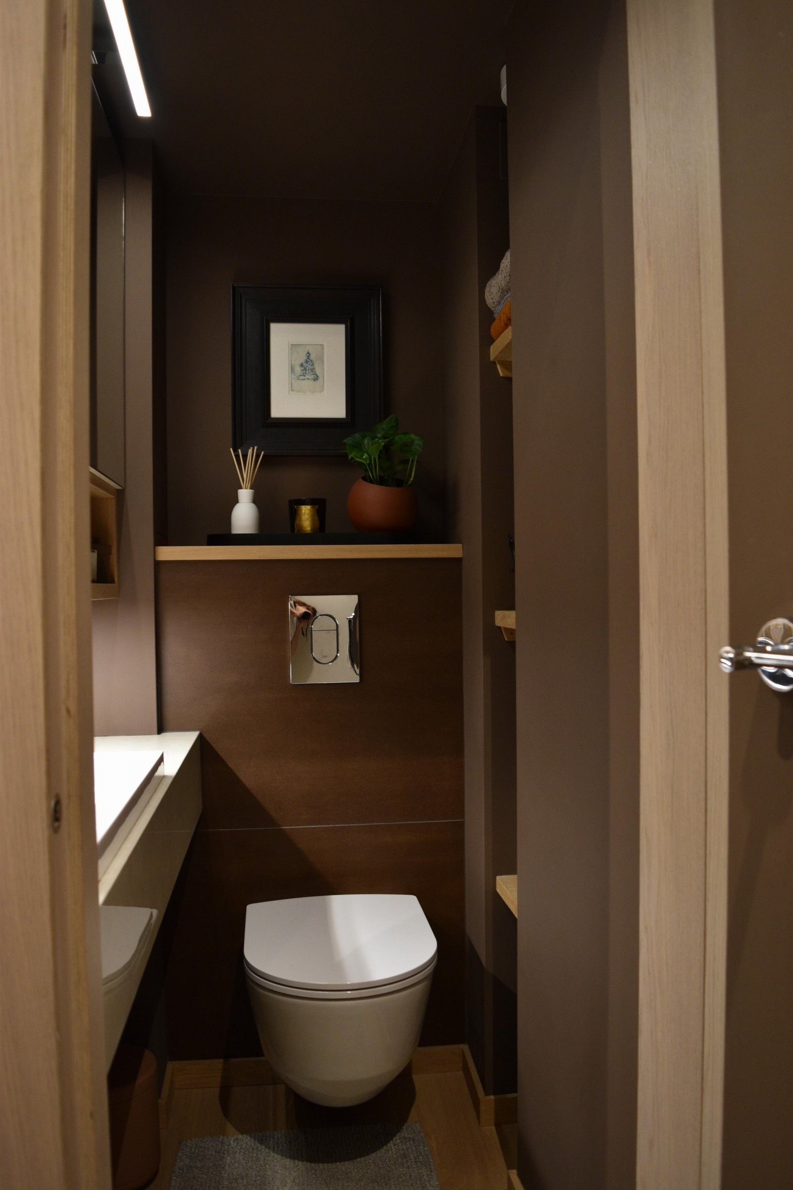 Praktisk og pent toalettrom med moderne innredning som veggmontert klosett, benk med vask og speilskap Galleribilde