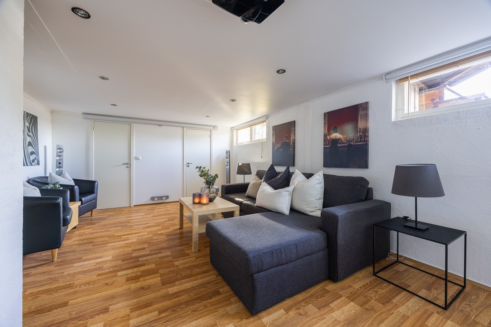 Kjellerstue med varmekabler, downlights og opplegg for filmprosjektor, lerret og AV-system. Galleribilde