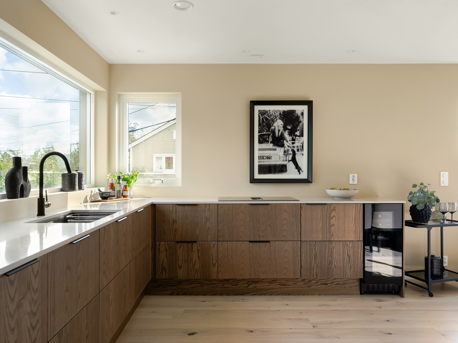 Benkeplaten i lys stein gir god arbeidsflate, og den minimalistiske induksjonstoppen med integrert ventilator sørger for både stil og effektivitet. Galleribilde